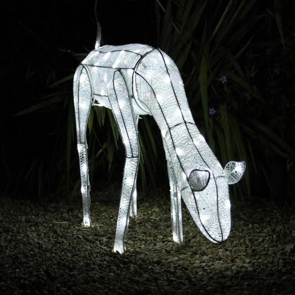 Large light-up grazing doe reindeer with a sleek white design, illuminated by bright LED lights, set against a dark garden backdrop