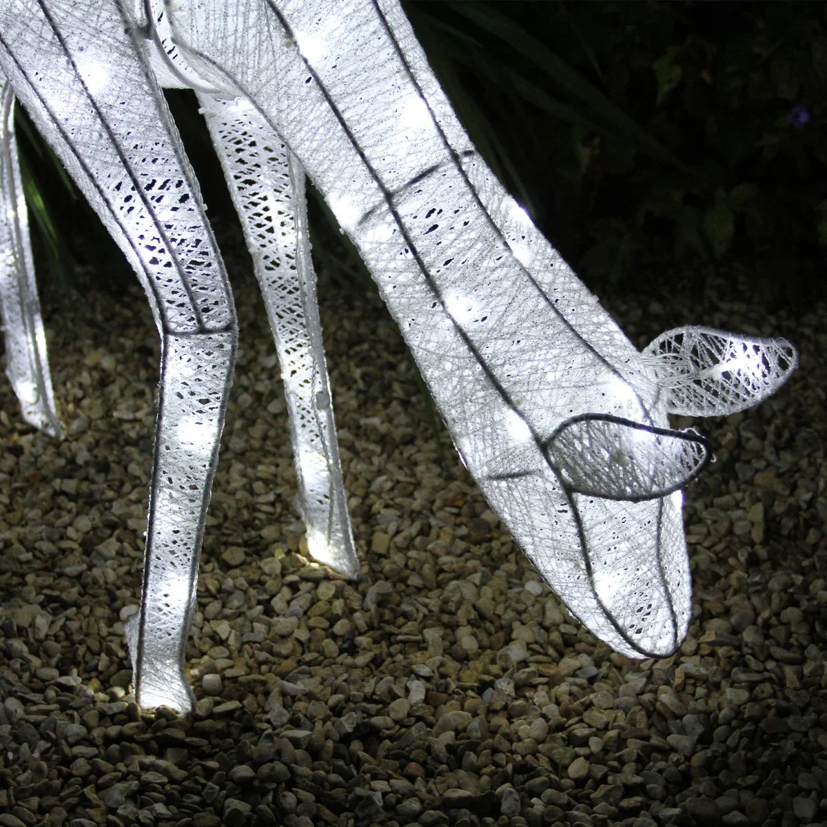 Glowing white reindeer stag with intricate lace-like texture, illuminated by soft white lights, set against a gravel background