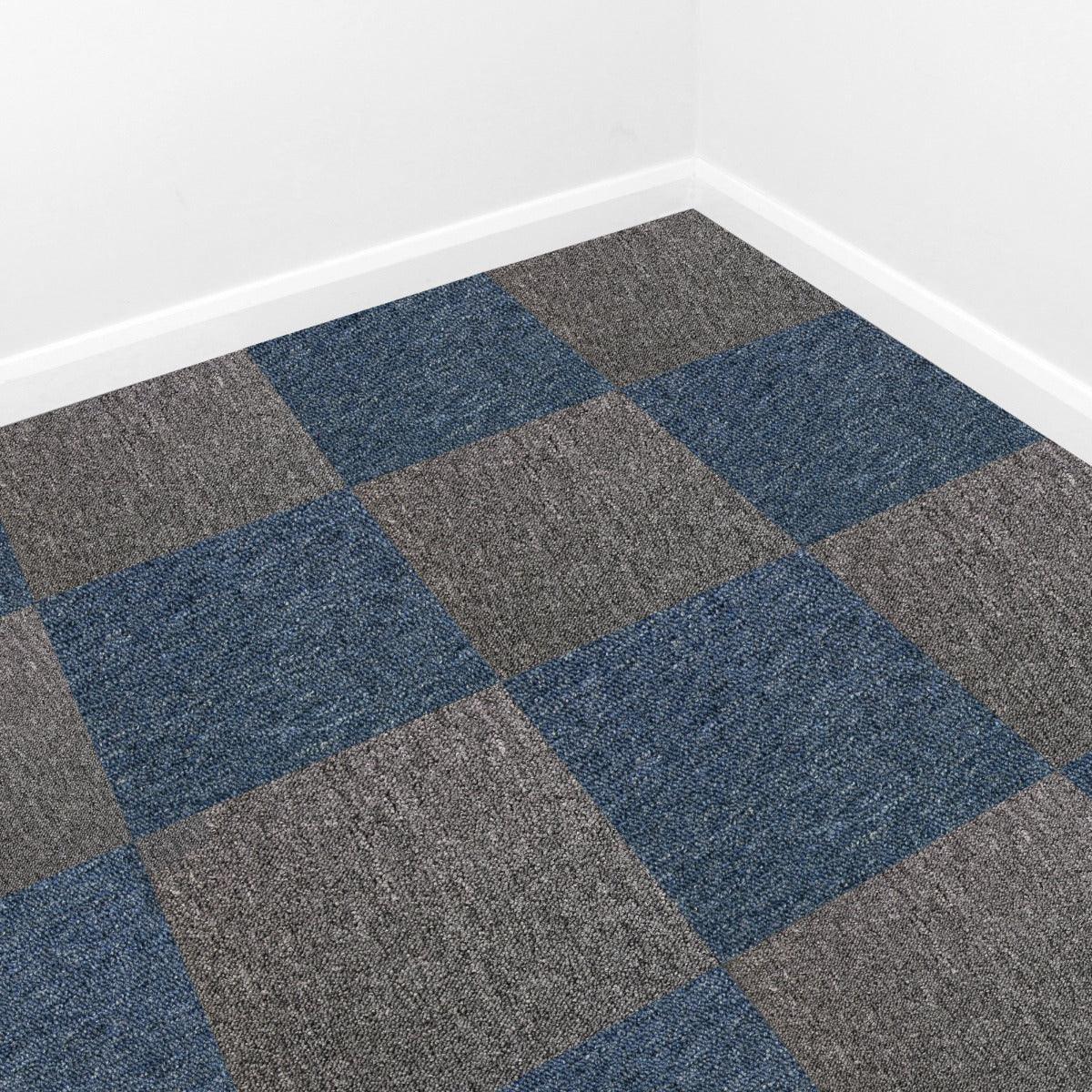 Storm blue and anthracite carpet tiles arranged in a checkerboard pattern, showcasing textured surfaces and modern design in a room corner