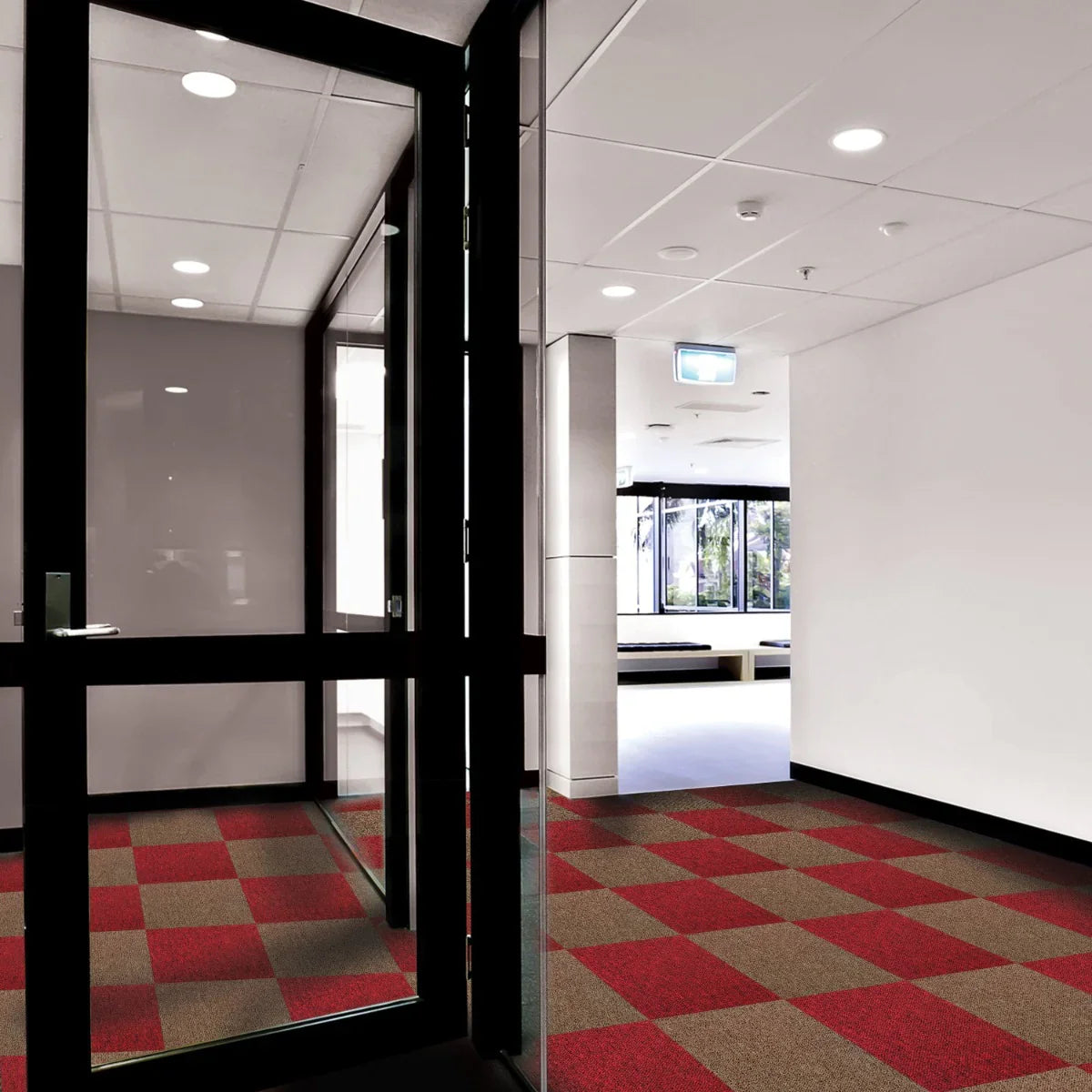 Scarlet red and sand carpet tiles arranged in a checkerboard pattern, enhancing a modern hallway with sleek glass doors and natural light