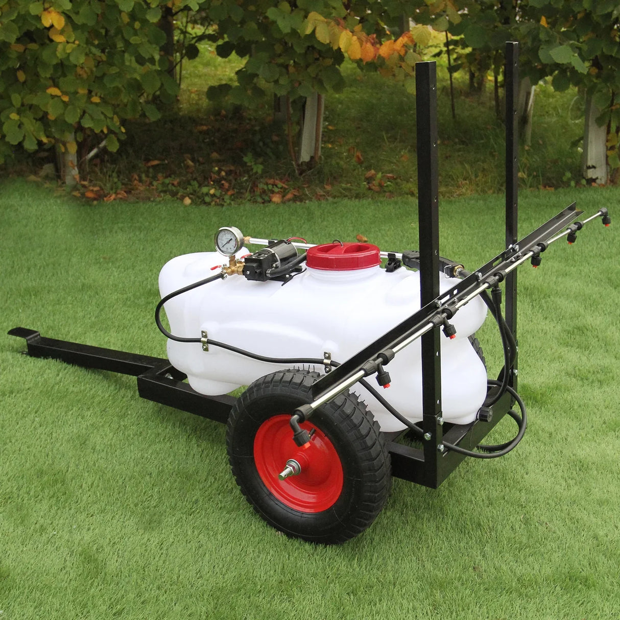 100L ATV trailer sprayer with white tank, red cap, black frame, and sturdy wheels, set against green grass background