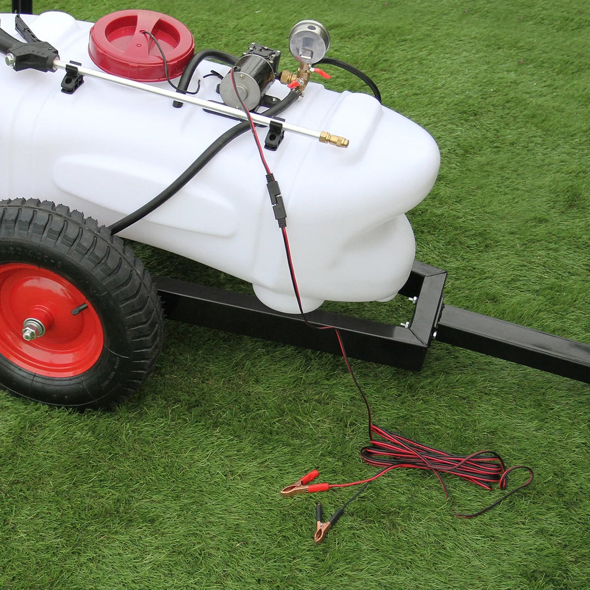 100L ATV trailer sprayer with white tank, red lid, black pump, and sturdy rubber tires on green grass background