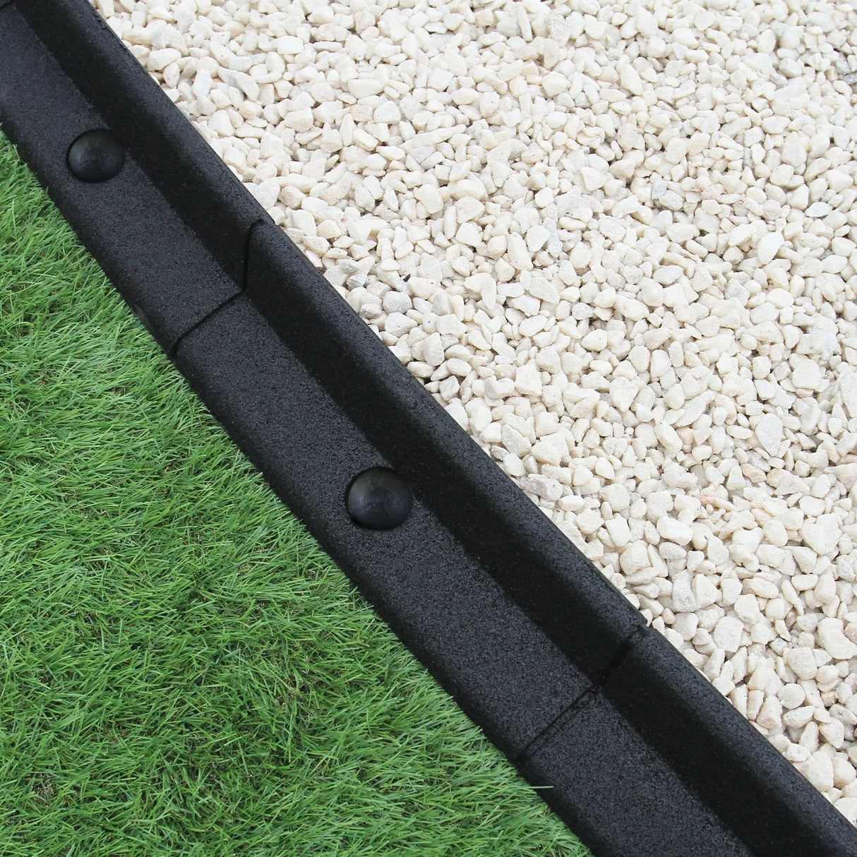 Flexible black lawn edging, 1.2m long, featuring a smooth texture and rounded shape, separating gravel and grass areas