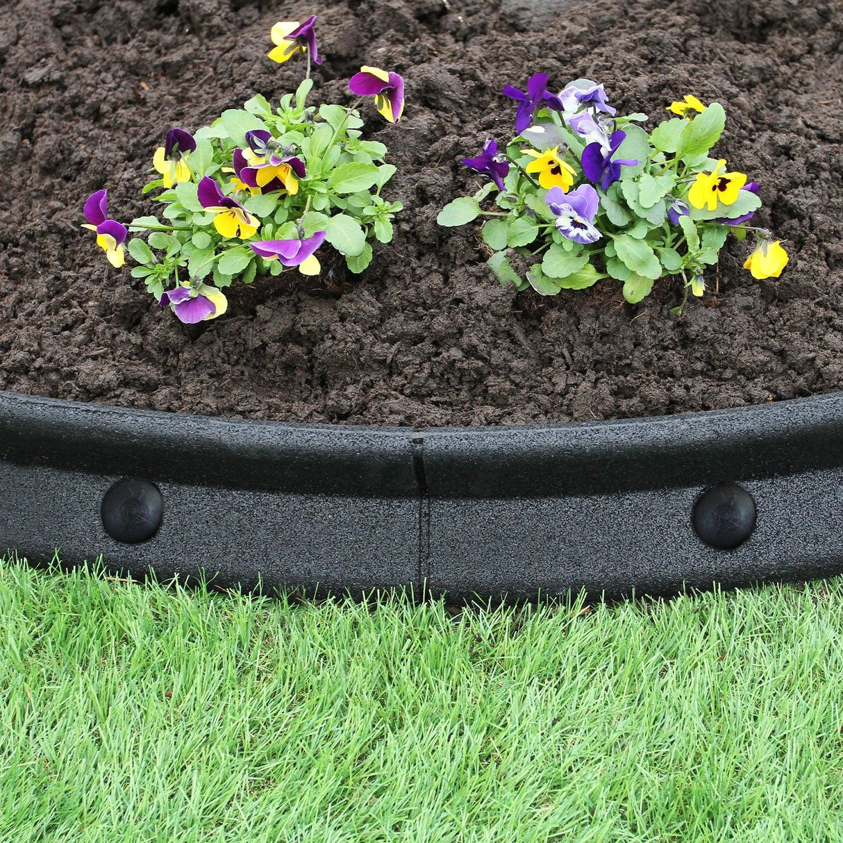 Flexible black lawn edging, 1.2m long, featuring smooth curves, with vibrant flowers and rich soil in the background