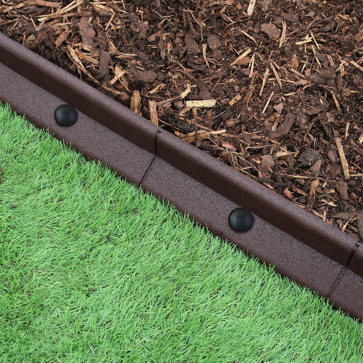 Flexible brown lawn edging, 1.2m long, featuring a smooth texture, neatly separating mulch from vibrant green grass