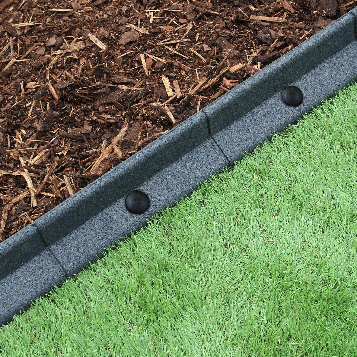 Flexible grey lawn edging measuring 1.2m, featuring a textured surface, neatly separating mulch from lush green grass