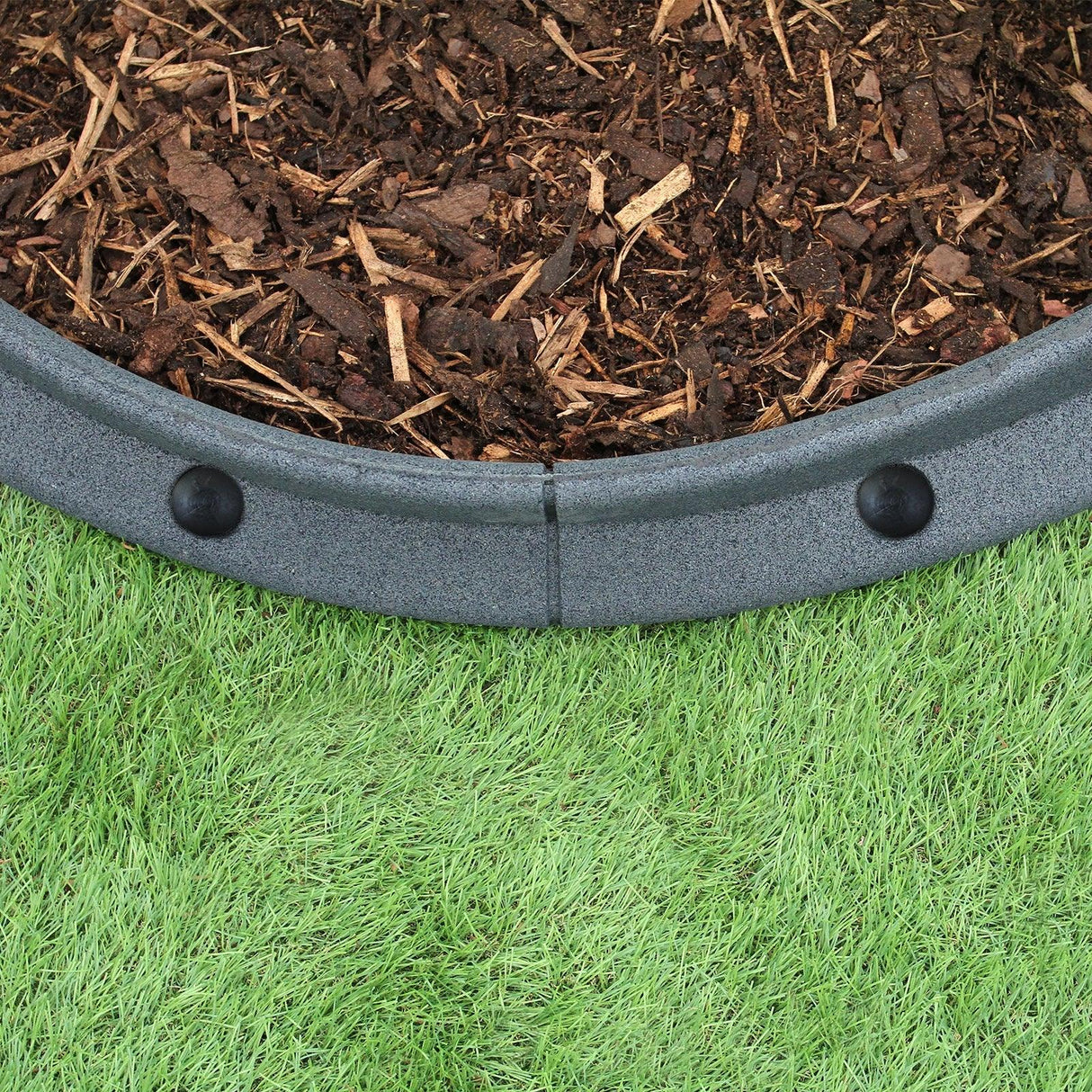 Flexible grey lawn edging, 1.2m long, featuring a smooth texture and rounded shape, installed around mulch on green grass