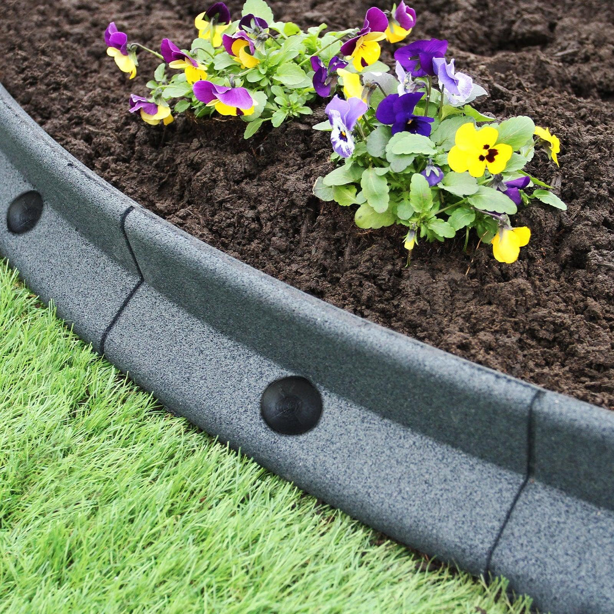 Flexible grey lawn edging, 1.2m x 6, curving around vibrant flowers and rich soil, enhancing garden aesthetics and structure