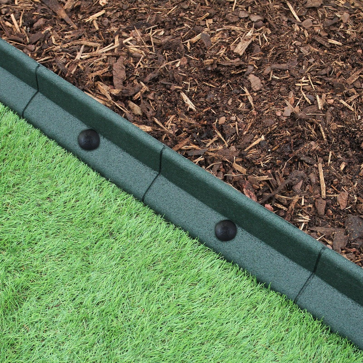 Flexible lawn edging in green, 1.2m long, featuring a smooth texture and rounded top, separating mulch from artificial grass
