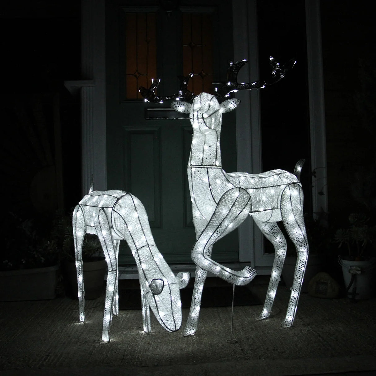 Large light-up stag and doe reindeer set, featuring a white wireframe design illuminated with soft white lights, perfect for festive decor