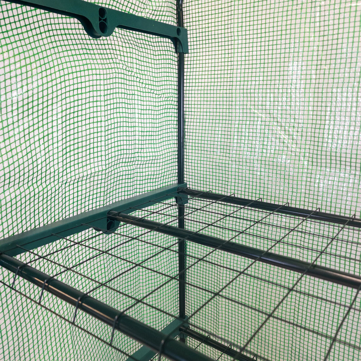 4-tier greenhouse with a green PE cover, featuring a sturdy metal frame and mesh netting for ventilation and plant support