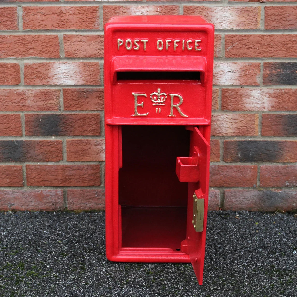 Bright red Royal Mail post box with stand, featuring gold lettering and crown emblem, showcasing an open door for mail collection