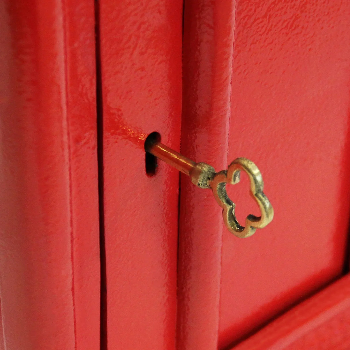 Bright red Royal Mail post box featuring a vintage brass keyhole, showcasing a smooth, glossy finish and classic design details