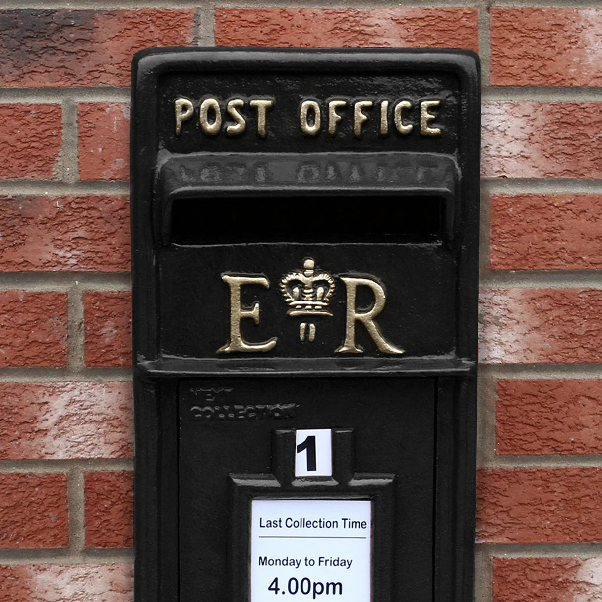 Black Royal Mail post box featuring gold lettering, a crown emblem, and a collection time notice, mounted against a brick wall