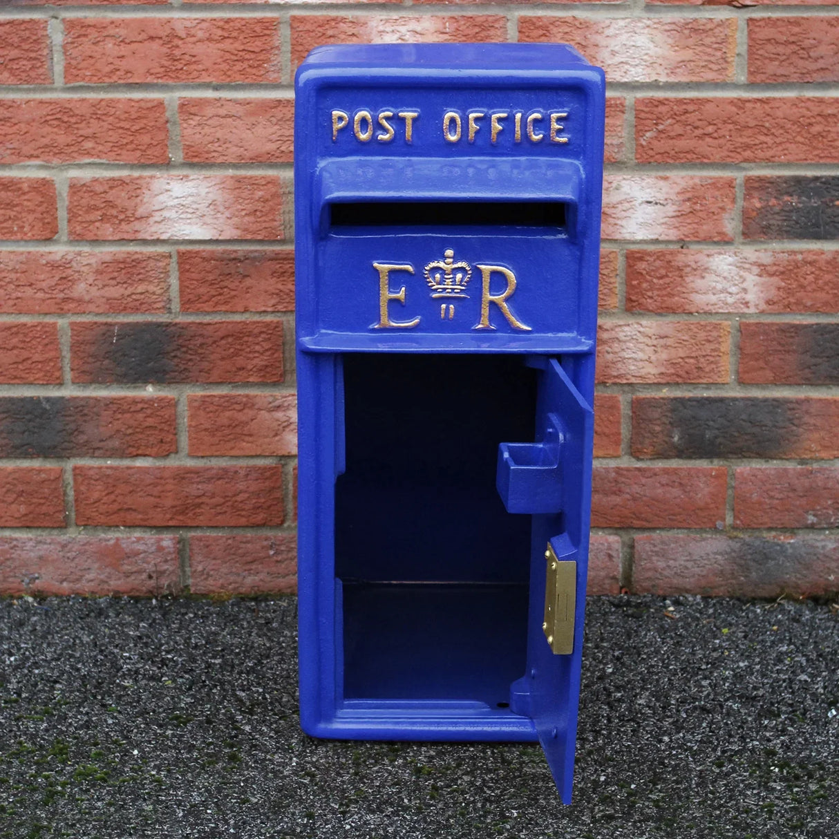 Blue Scottish post box with stand, featuring a royal ER emblem, textured finish, and an open door against a brick background