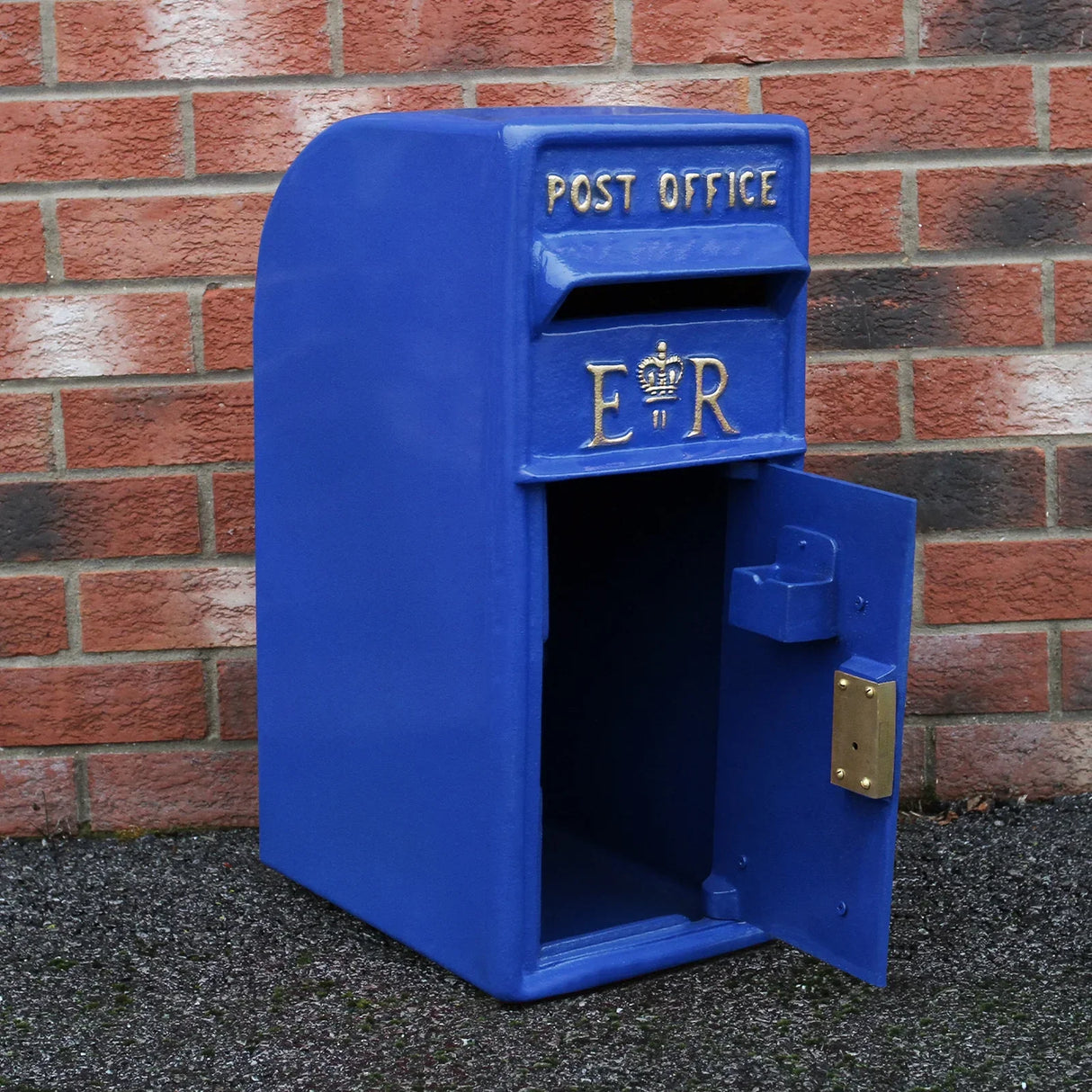 Bright blue Scottish post box with gold lettering, featuring an open door and classic design, set against a brick wall background