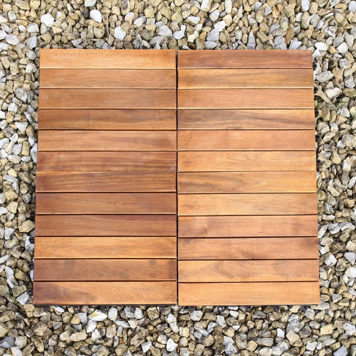 Natural wooden decking tiles with a smooth finish, arranged in a grid pattern, set against a backdrop of small stones
