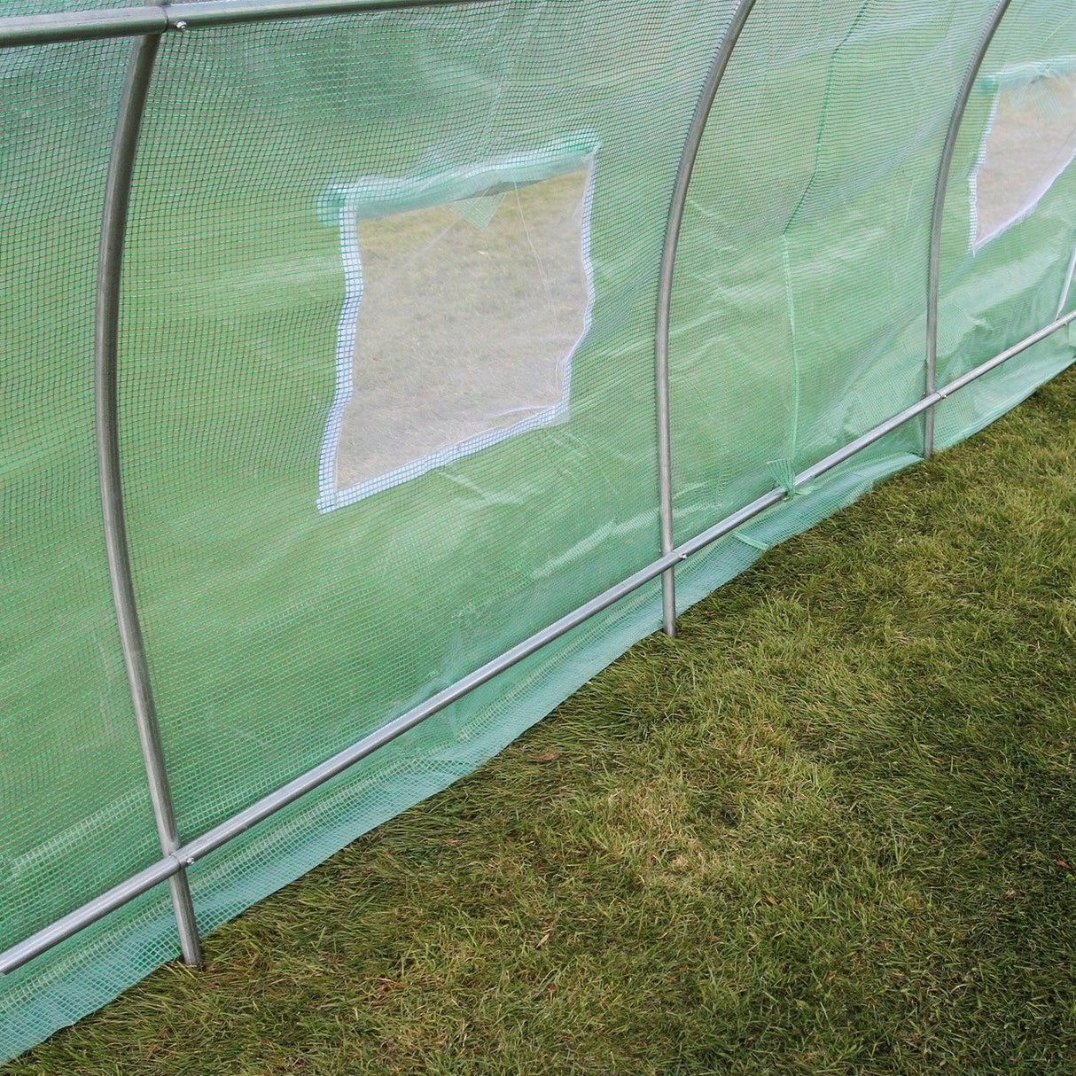 Green mesh polytunnel with 25mm frame, measuring 6m x 3m, showcasing side windows and sturdy structure on grass surface