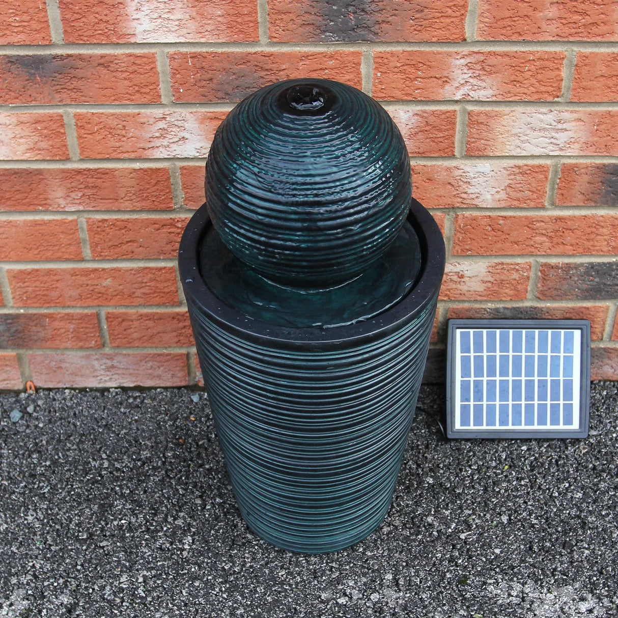 Round ball solar water feature with textured dark green finish, cylindrical base, and solar panel for outdoor decoration