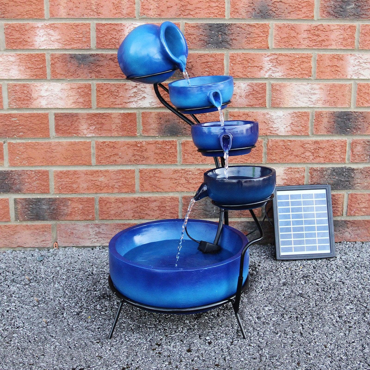 Blue 4 tier spilling bowls water feature with a sleek design, showcasing vibrant blue hues and flowing water against a brick wall