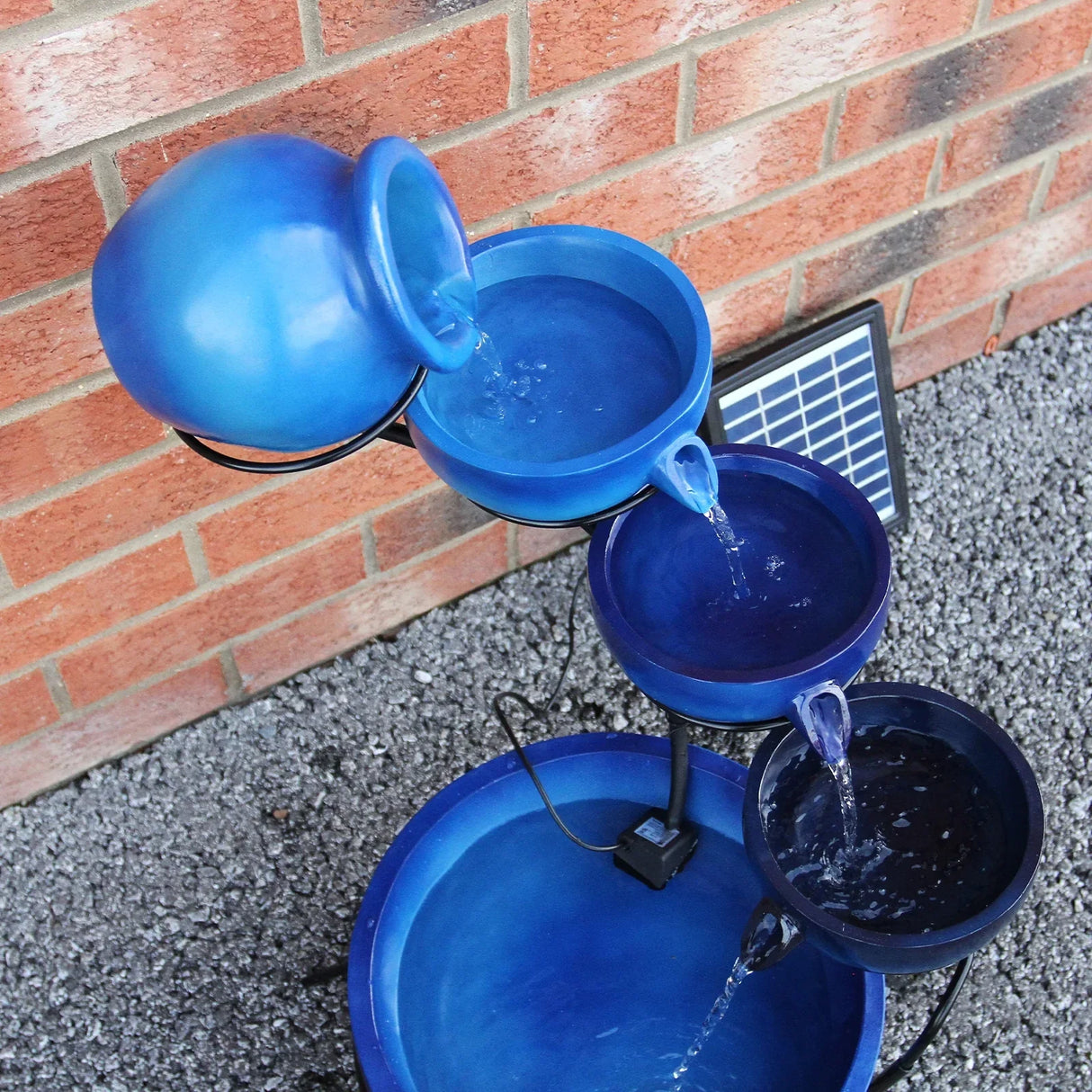Blue 4 tier spilling bowls water feature with a glossy finish, cascading water from each bowl against a brick background