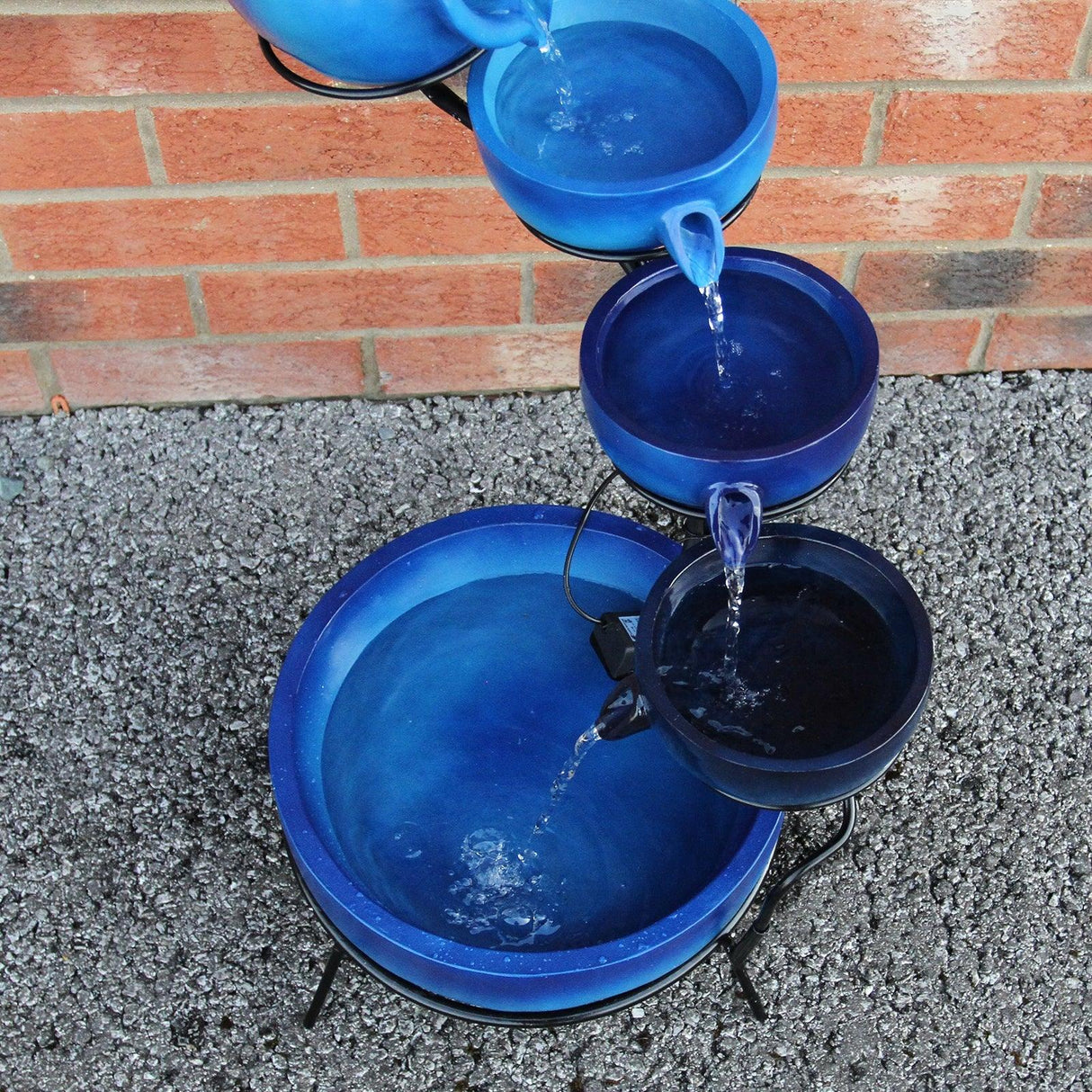 Blue 4 tier spilling bowls water feature with smooth ceramic texture, cascading water, and a vibrant gradient of blue shades