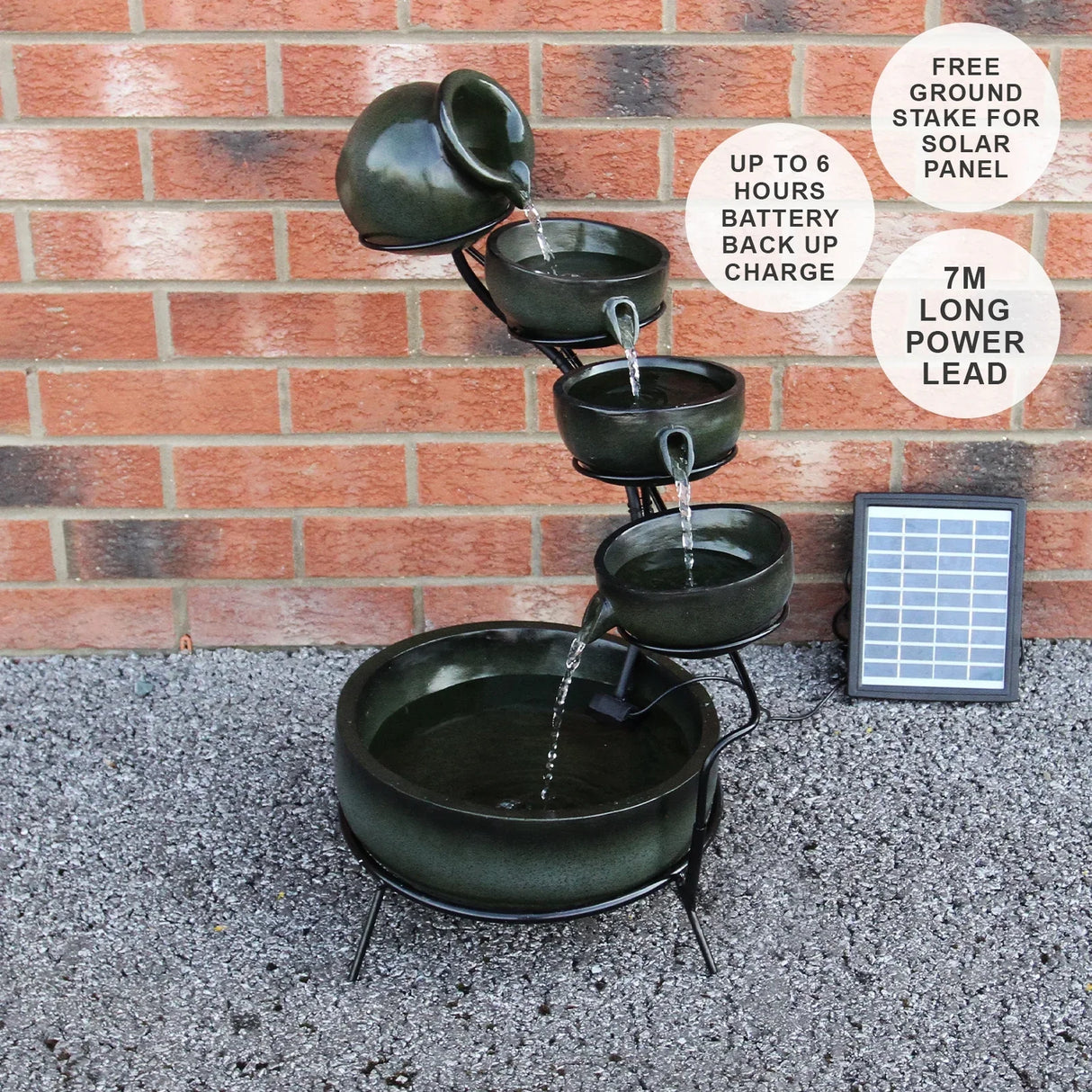 Green 4 tier spilling bowls water feature with a sleek design, ceramic-like texture, and flowing water, set against a brick wall