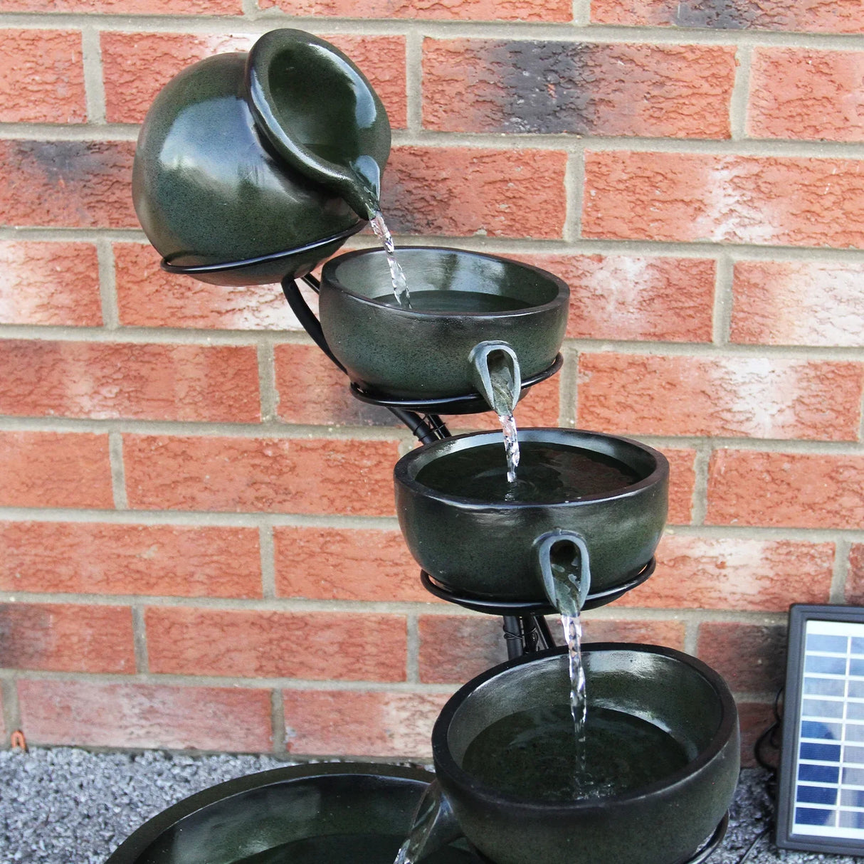 Green 4 tier spilling bowls water feature with a glossy finish, cascading water from each bowl against a brick wall backdrop