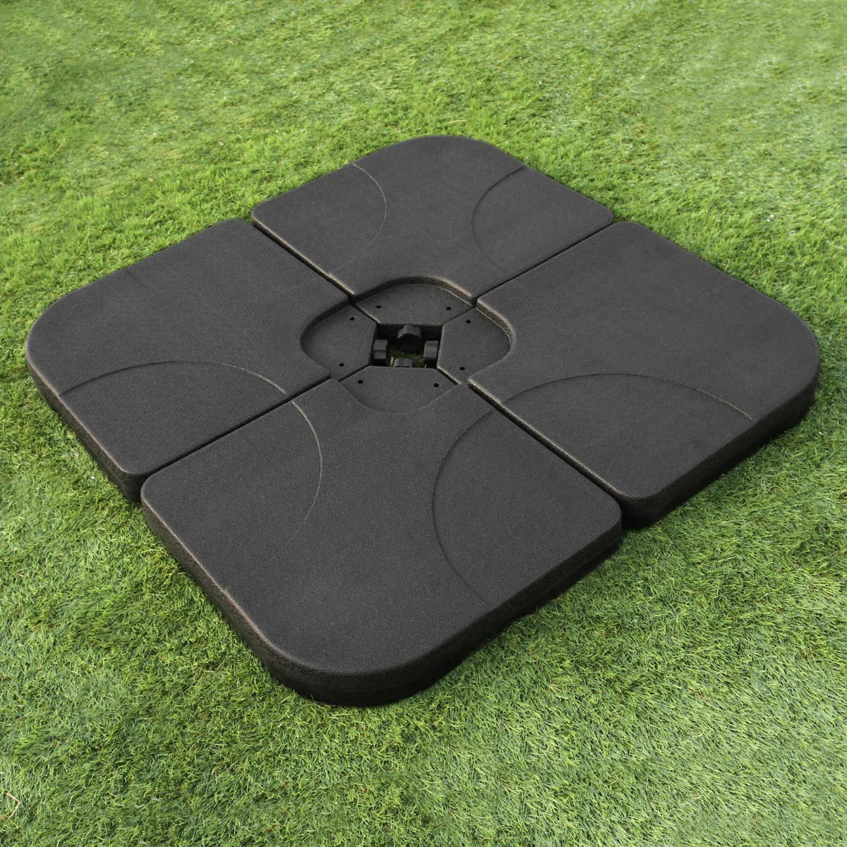 Heavy-duty black cantilever parasol base with a square shape, featuring four interlocking sections for stability on grass surfaces