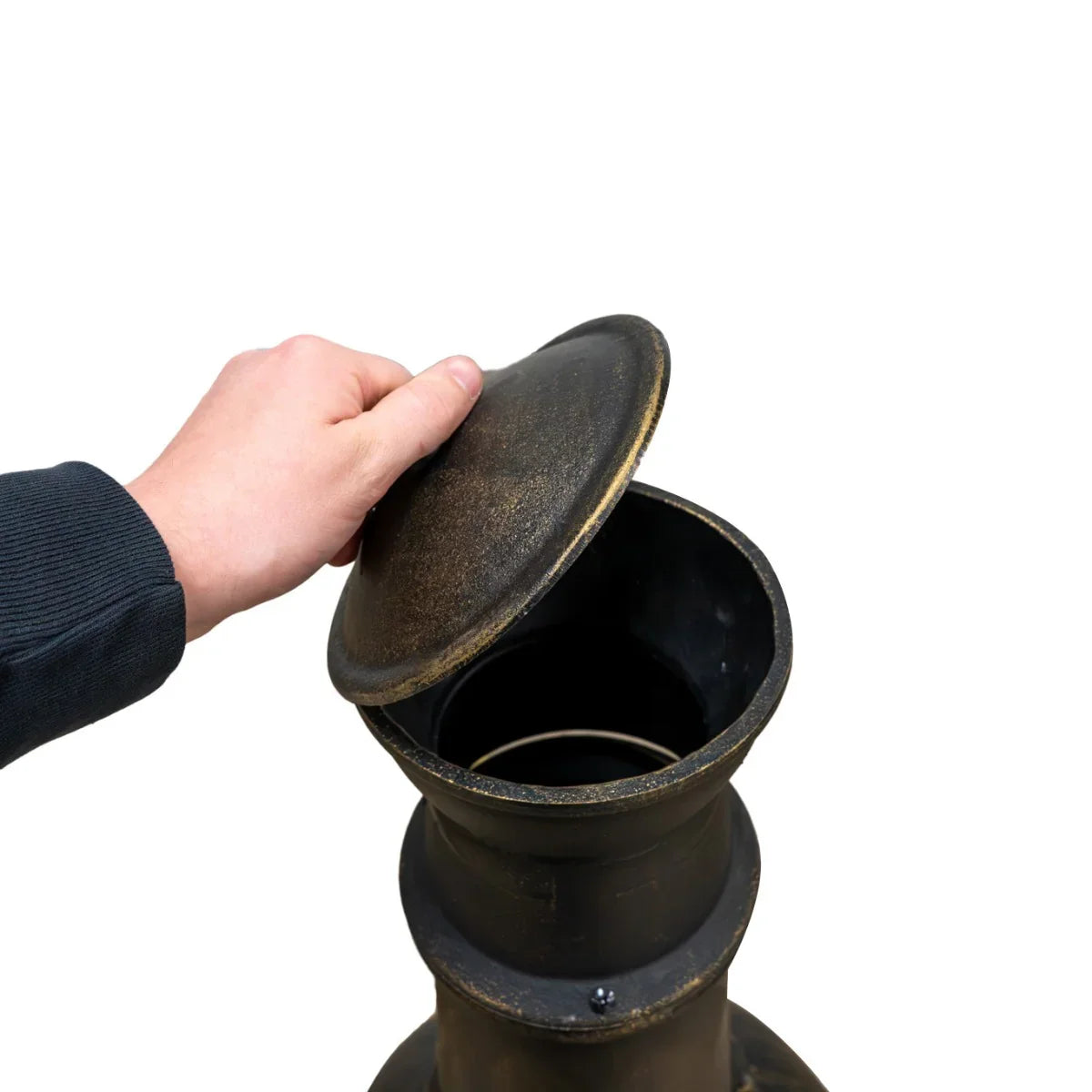 Hand lifting the lid of a black cast iron chiminea, showcasing its sturdy construction and classic design for outdoor warmth