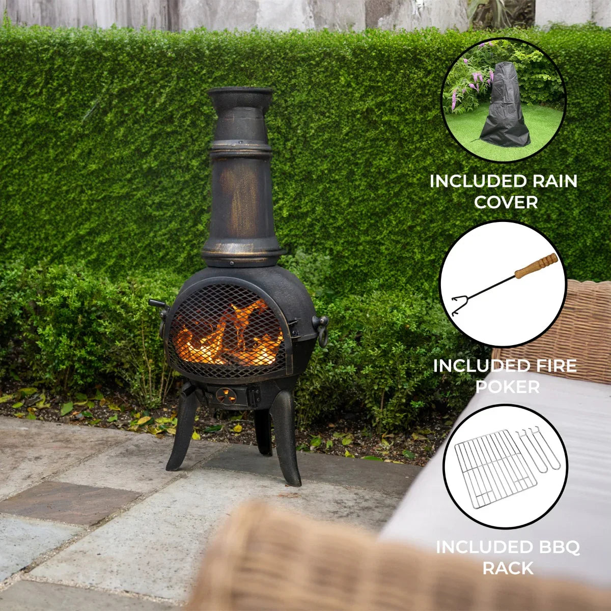 Cast iron chiminea with a tall chimney, glowing fire inside, and included rain cover, fire poker, and BBQ rack in a garden setting