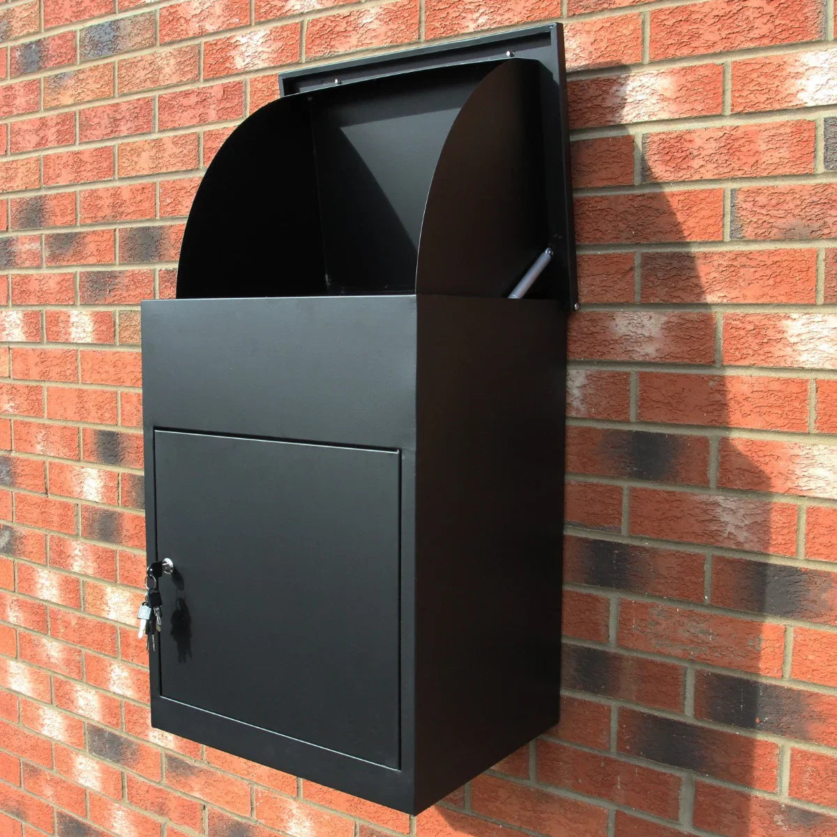Sleek black parcel post box mounted on a brick wall, featuring a curved top, secure lock, and spacious storage compartment for deliveries