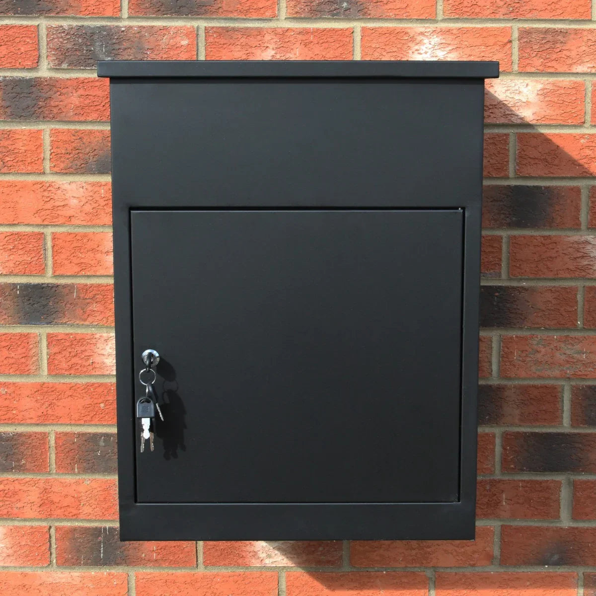 Sleek black parcel post box mounted on a brick wall, featuring a secure lock and a minimalist design for modern homes
