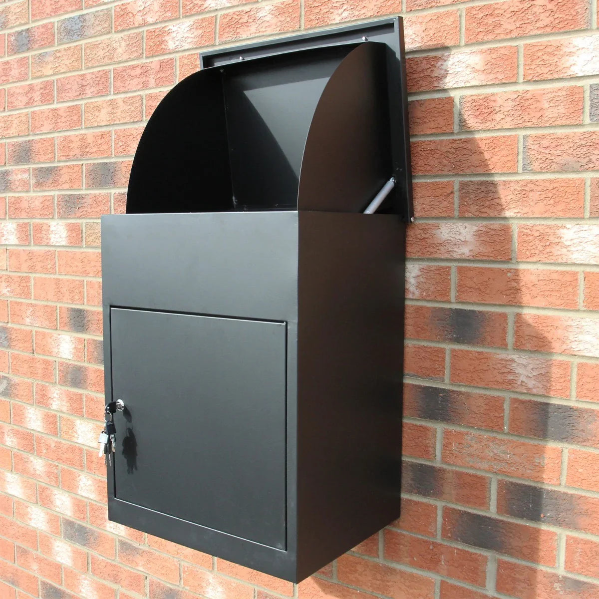 Sleek black parcel post box mounted on a brick wall, featuring a curved top, secure lock, and spacious front opening for deliveries