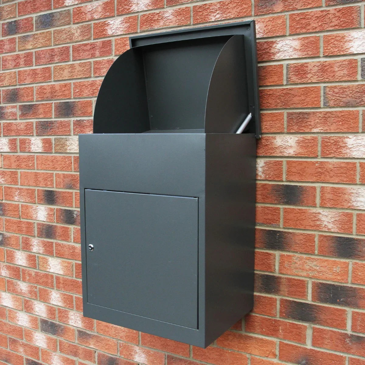 Stylish grey parcel post box mounted on a brick wall, featuring a curved top, secure locking door, and durable metal construction