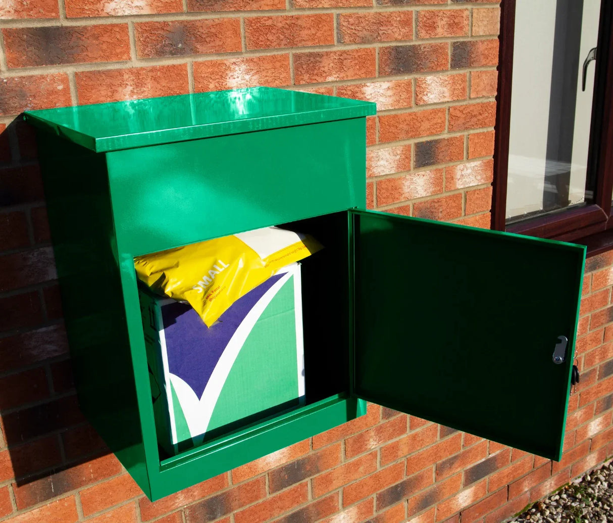 Bright green parcel post box mounted on a brick wall, featuring an open door revealing a yellow and green package inside