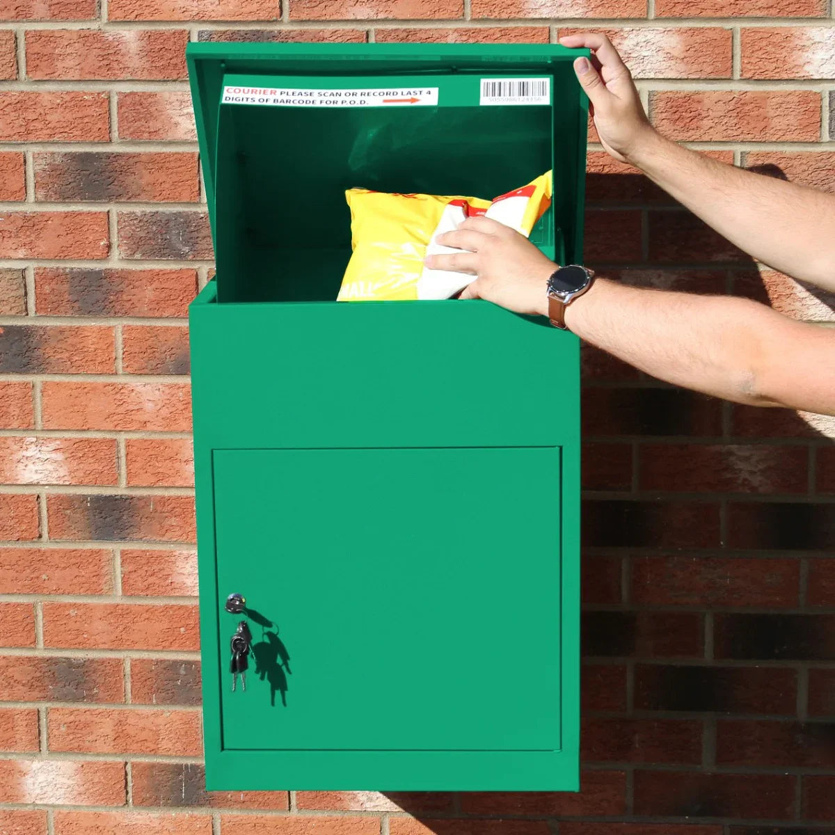 Bright green parcel post box with a secure lock, open lid revealing packages inside, mounted against a brick wall