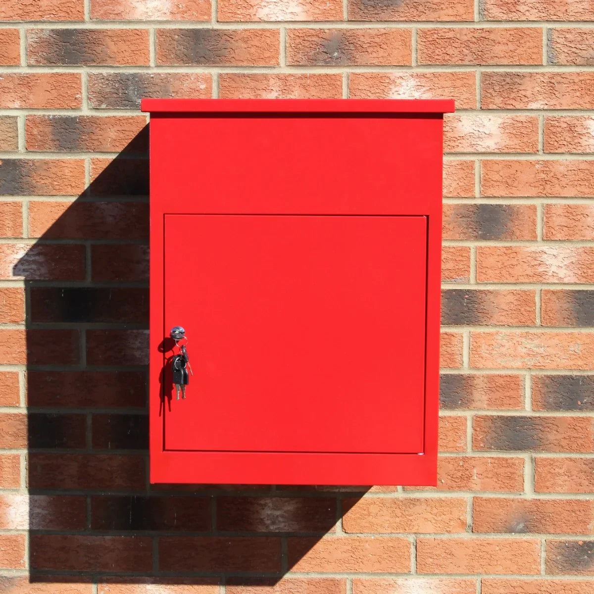 Bright red parcel post box mounted on a brick wall, featuring a flat top, a secure lock, and a smooth, glossy finish