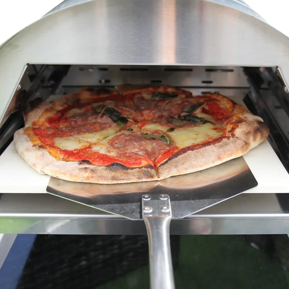 Outdoor table top pizza oven with a freshly baked pepperoni pizza, featuring a crispy crust, melted cheese, and vibrant tomato sauce