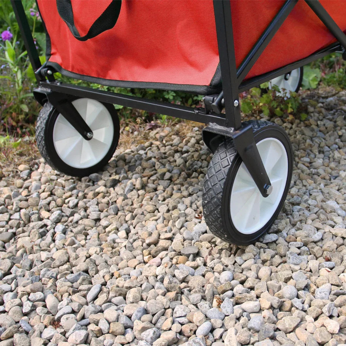 Foldable garden cart in vibrant red with durable fabric, sturdy black frame, and large white wheels on a gravel surface