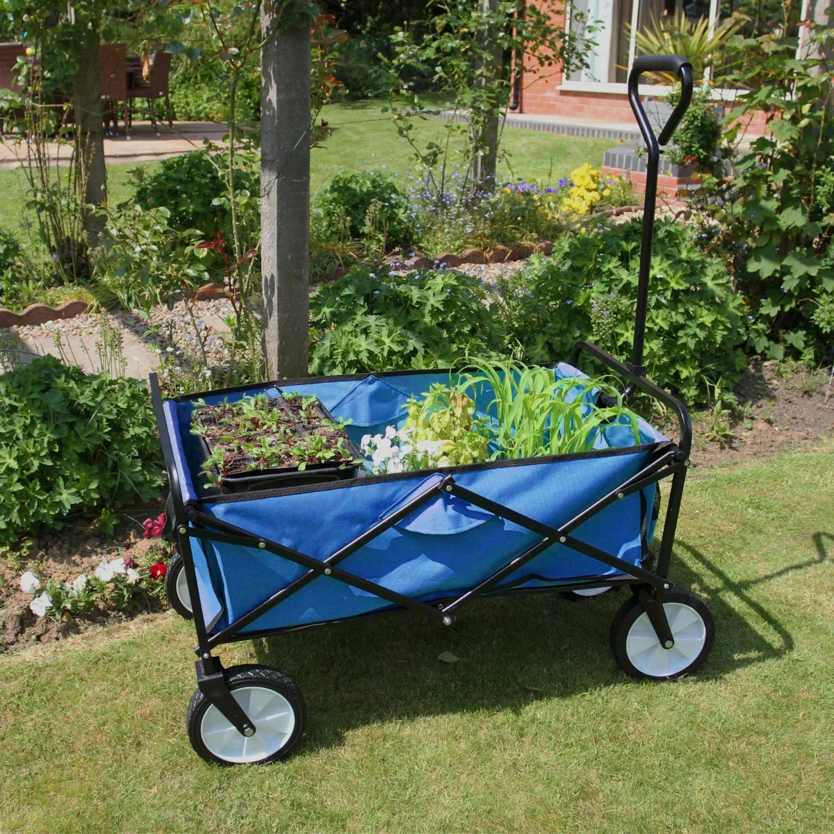Foldable blue garden cart with black frame, spacious interior holding plants, and sturdy wheels, set in a lush garden environment