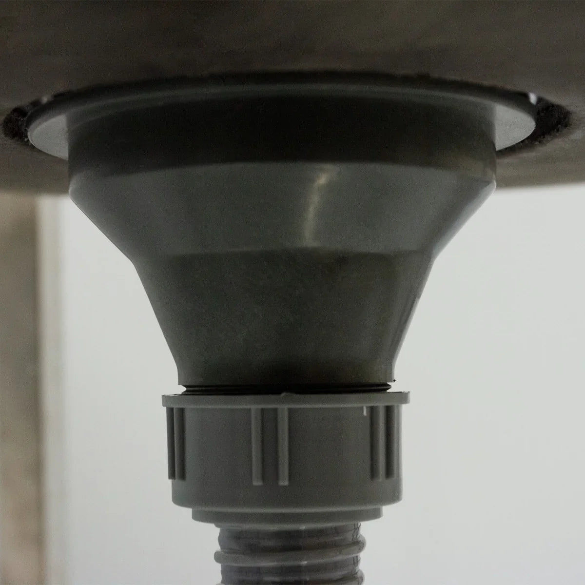 Portable stainless steel camping sink featuring a funnel-shaped drain with a gray plastic connector for easy water disposal