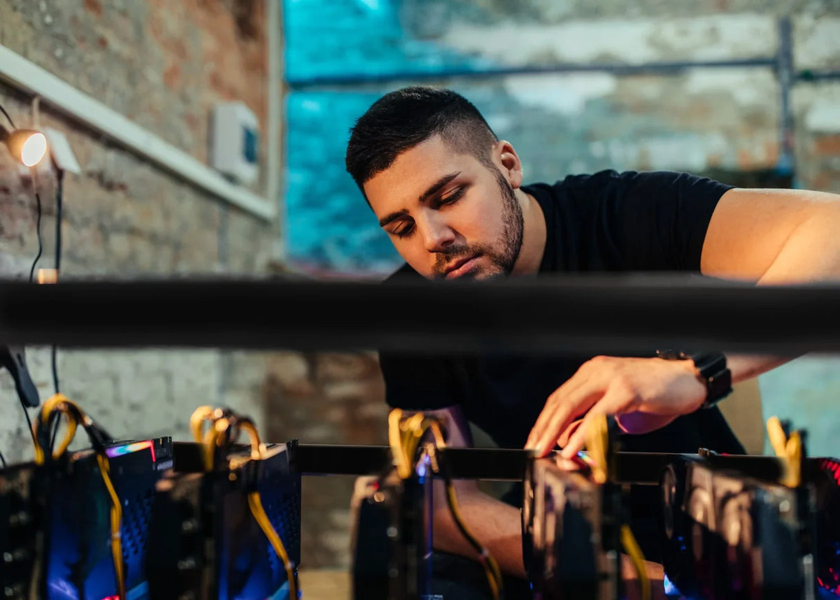 A person adjusting a 6-8 GPU mining rig frame with multiple GPUs, showcasing a sleek black design and vibrant LED lights