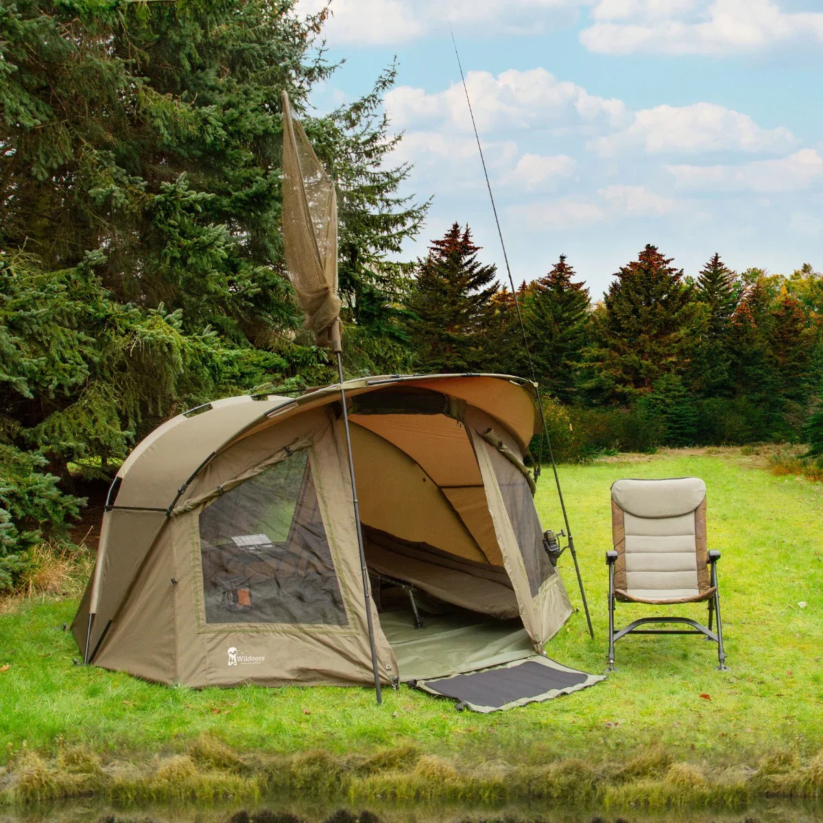Spacious 2-man fishing bivvy in olive green, featuring mesh windows, a sturdy frame, and a comfortable folding chair beside it