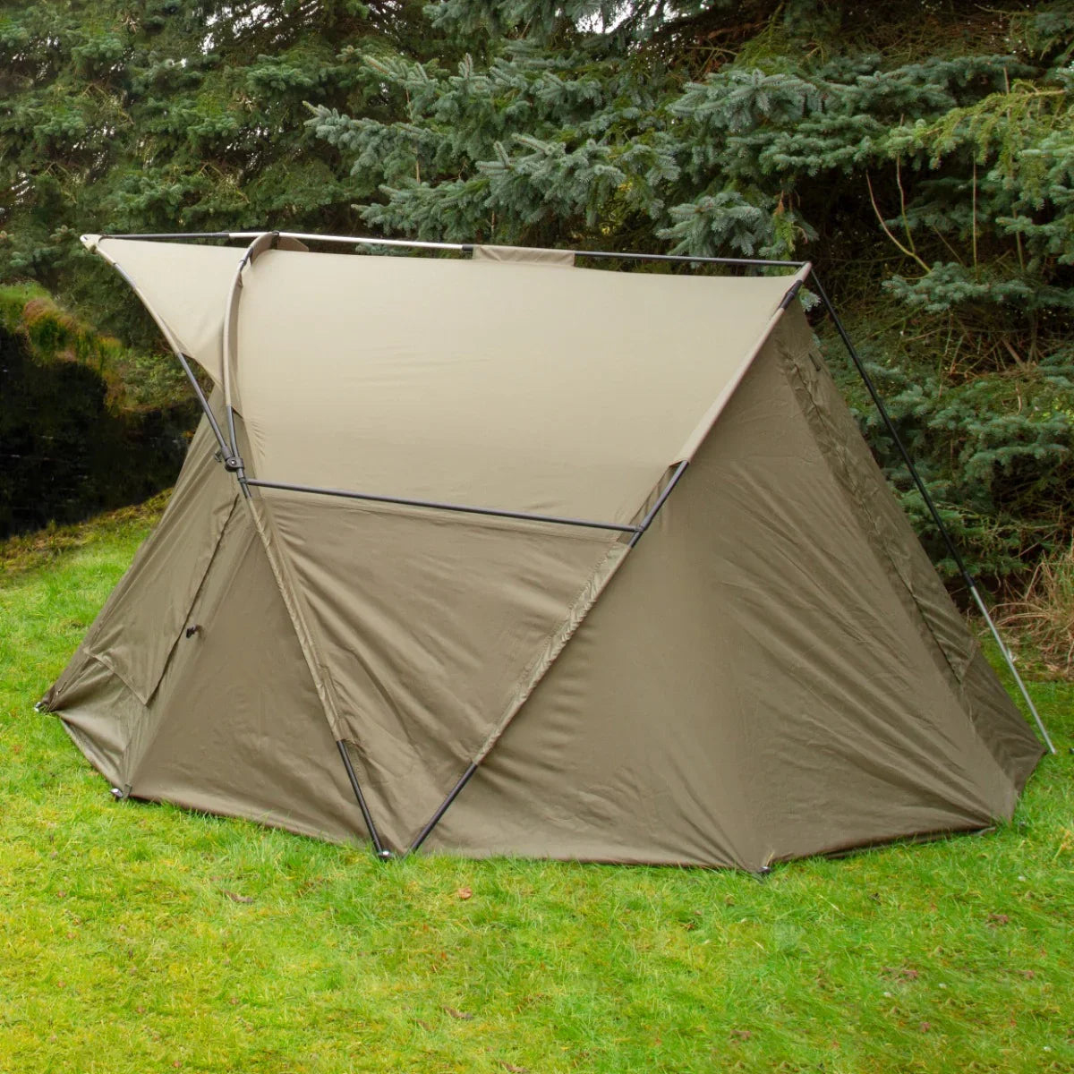 Spacious 2-man fishing bivvy in earthy brown, featuring a sturdy frame and waterproof fabric, set against a lush green backdrop