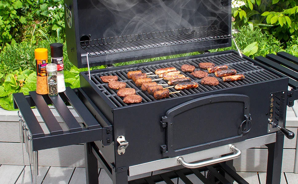 Black gas grill with sizzling meats and smoke, surrounded by fresh greenery and condiments on a wooden deck