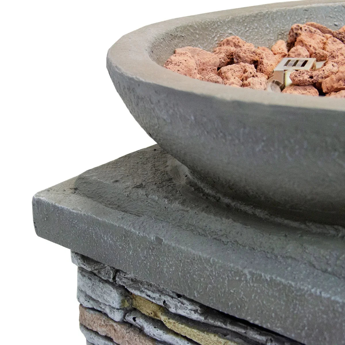 Round stone gas fire pit heater with textured gray bowl, surrounded by decorative lava rocks, set on a stacked stone base