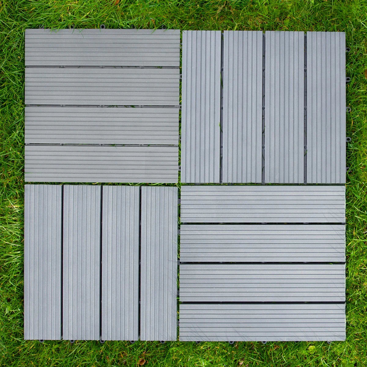 Grey WPC decking floor tiles, 30x30cm, featuring a textured surface and slatted design, arranged in a square on green grass