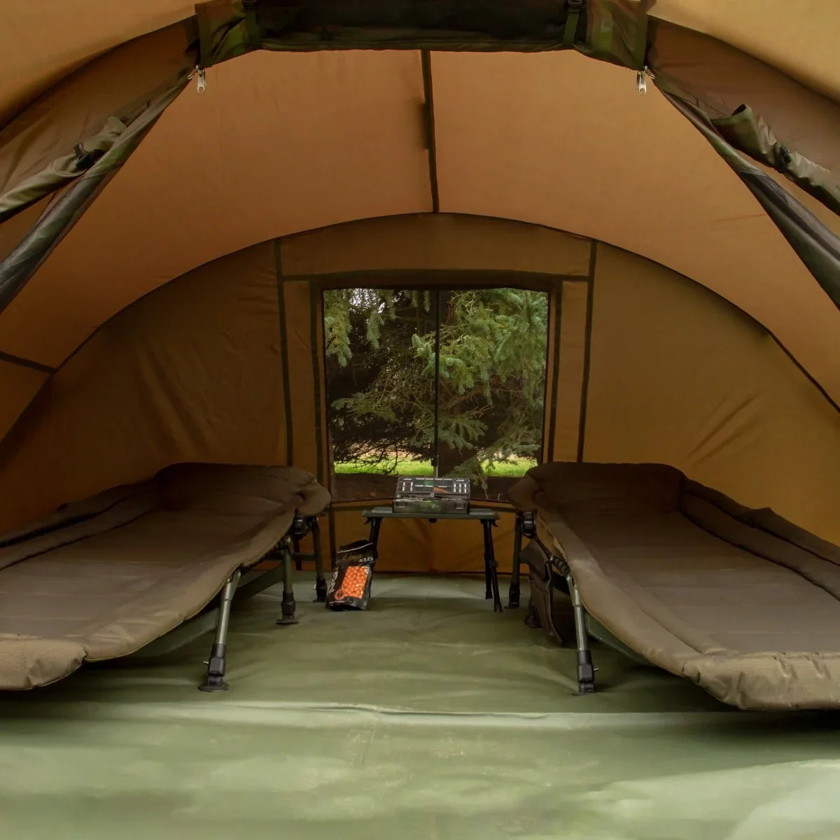 Spacious 2-man fishing bivvy with a tan interior, featuring two beds and a table, ideal for camping and fishing trips
