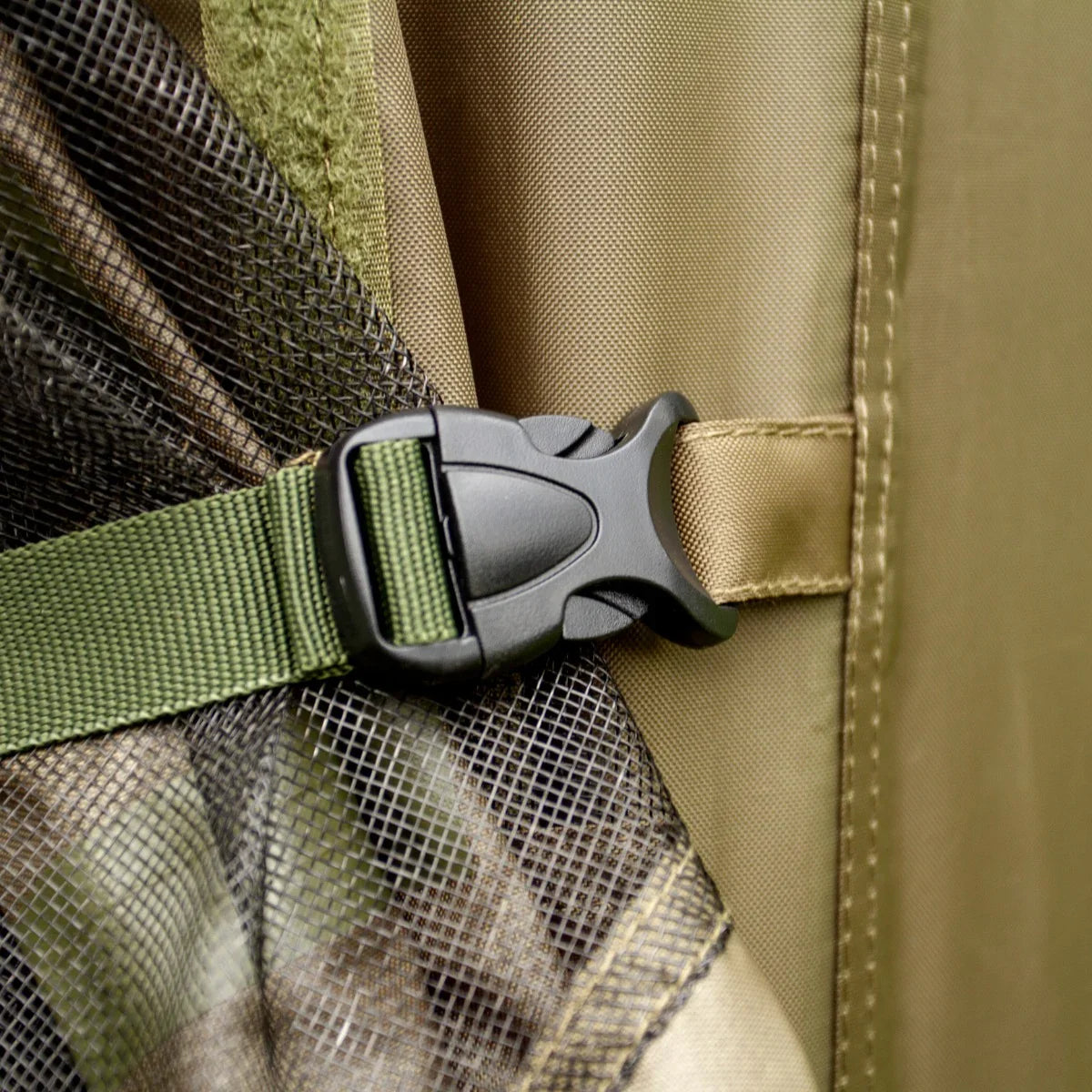 Close-up of a durable green buckle fastening on a fishing bivvy, showcasing the textured fabric and camouflage pattern details